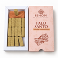 An open white box of ISHOM Palo Santo Smudge Incense Bricks next to its pink packaging box, showing the light tan incense sticks and a brown smudge sample on a white background.