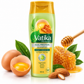 Vatika Naturals Egg Protein Shampoo bottle centered on a white background, surrounded by egg halves with yolks, almonds, honeycomb, honey, and green leaves. The bottle is yellow-green with a gold cap, and the label reads Hair Strength and 400 ml.