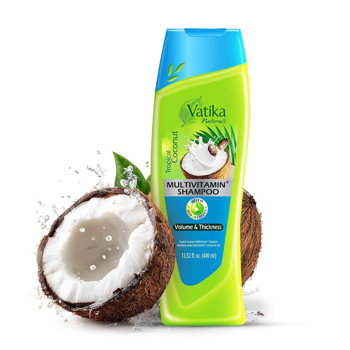 A bottle of Vatika Naturals Tropical Coconut Multivitamin Shampoo stands upright on a white background, styled with a halved coconut and green leaves. The bottle is bright lime green with a blue cap and blue label sections.